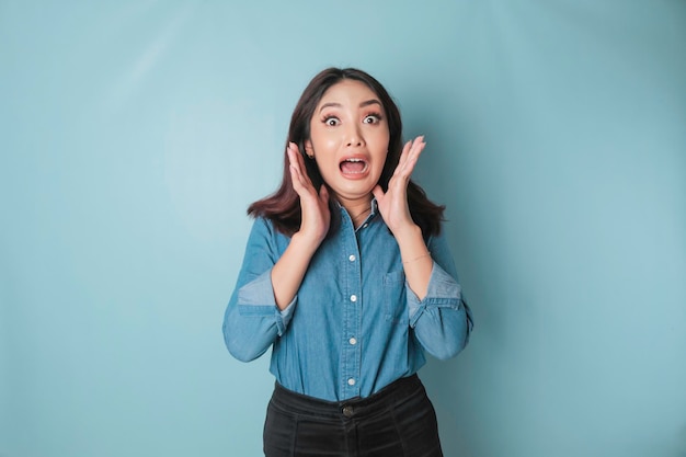 Portrait d'une jeune femme asiatique isolée par un fond bleu se sentant frustrée par l'expression du visage impuissant