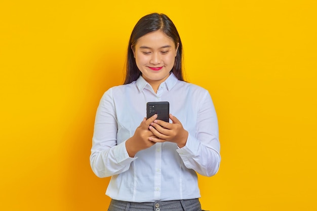 Portrait d'une jeune femme asiatique joyeuse tenant un smartphone tout en regardant la caméra