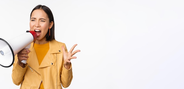 Portrait d'une jeune femme asiatique manifestant criant dans un mégaphone et protestant debout confiant aga