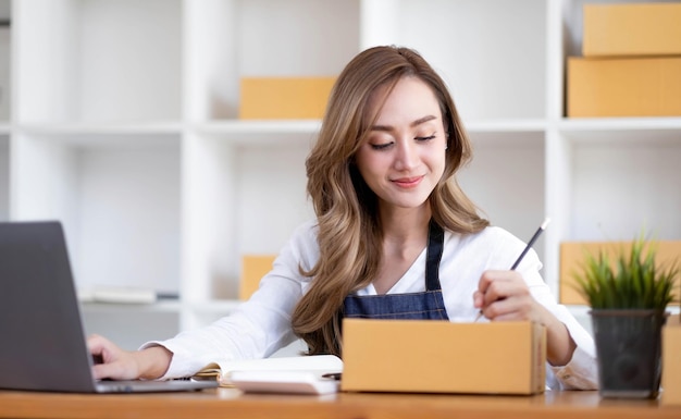 Portrait d'une jeune femme asiatique PME travaillant avec une boîte à la maison le lieu de travail démarrage propriétaire d'une petite entreprise petite entreprise entrepreneur PME ou entreprise indépendante en ligne et concept de livraison