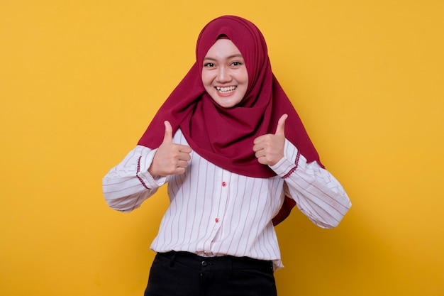 Portrait de jeune femme asiatique portant le hijab donne deux pouces et regarde joyeusement l'expression