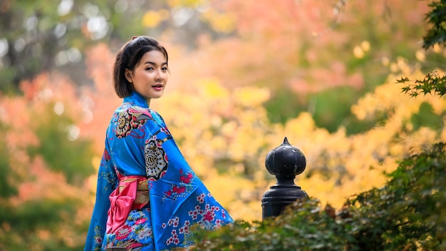 Portrait de jeune femme asiatique portant l'histoire de la mode kimono bleu japonais debout dans le parc à la saison d'automne au japon