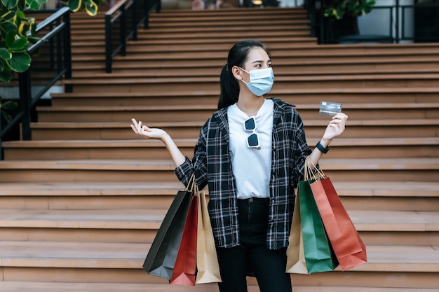 Portrait de jeune femme asiatique portant un masque de protection assis dans les escaliers avec un sac en papier