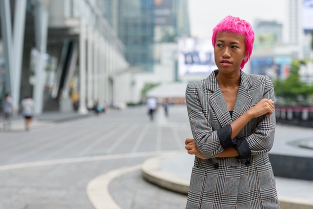 Portrait de jeune femme asiatique rebelle aux cheveux roses dans les rues de la ville à l'extérieur