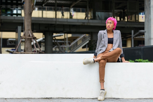 Portrait de jeune femme asiatique rebelle aux cheveux roses dans les rues de la ville à l'extérieur