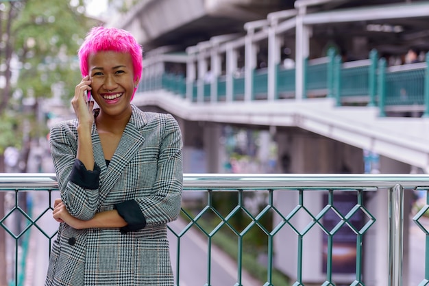 Portrait de jeune femme asiatique rebelle aux cheveux roses à passerelle dans la ville en plein air
