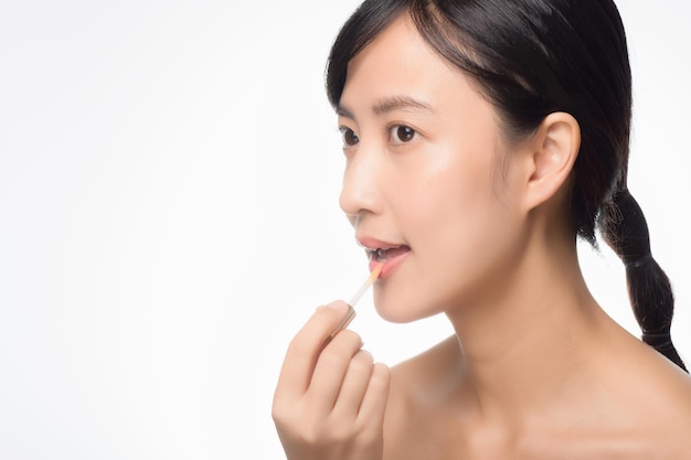 Portrait jeune femme asiatique regardant un miroir appliquant du rouge à lèvres de maquillage dans la chambre
