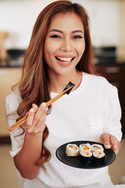 Portrait d'une jeune femme asiatique séduisante avec une assiette à manger avec de délicieux sushis