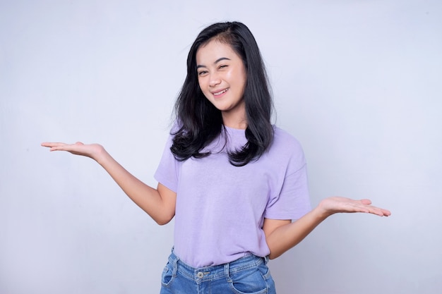 Portrait d'une jeune femme asiatique souriante avec une expression joyeuse, montre quelque chose d'étonnant dans un espace vide dans un tissu décontracté isolé sur un mur