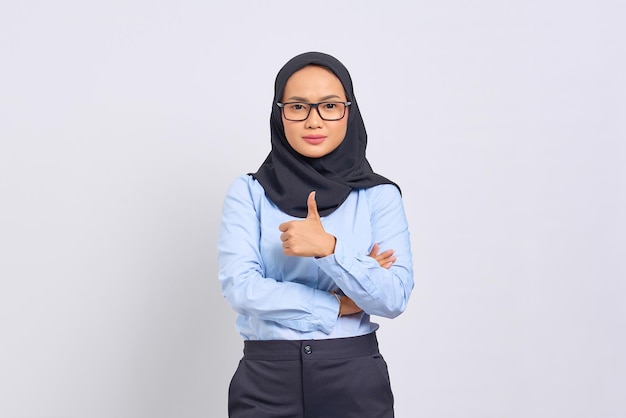 Portrait d'une jeune femme asiatique souriante montrant un geste de pouce levé, approuvant l'expression en regardant la caméra avec un succès montrant isolé sur fond blanc