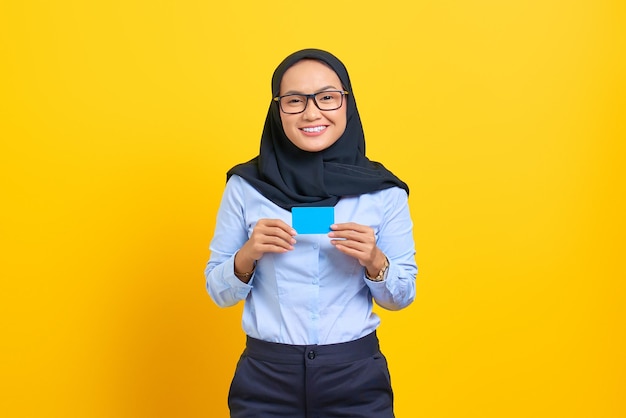 Portrait de jeune femme asiatique souriante tenant une carte vierge avec bonne humeur isolée sur fond jaune