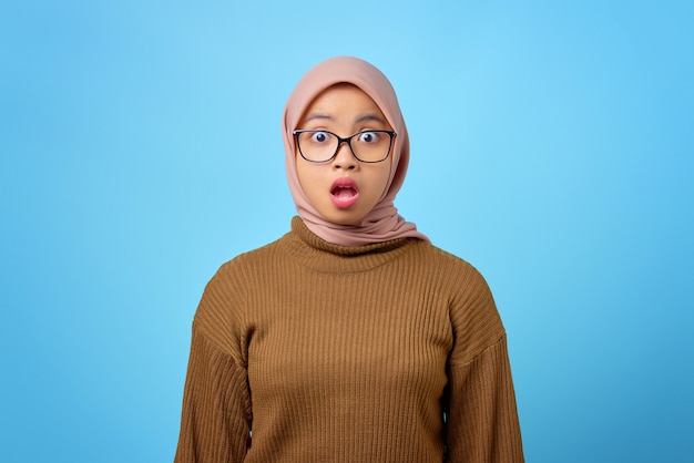 Portrait de jeune femme asiatique surprise avec la bouche ouverte sur fond bleu