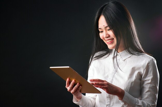 Portrait d'une jeune femme asiatique avec une tablette sur fond noir