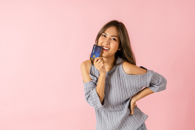 Photo portrait d'une jeune femme asiatique tenant une carte de crédit, elle pense faire du shopping