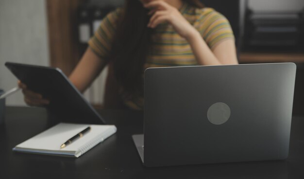 Portrait d'une jeune femme asiatique travaillant à la main sur une tablette informatique dans un bureau moderne. Faire un rapport d'analyse comptable sur les données d'investissement immobilier Concept de systèmes financiers et fiscaux