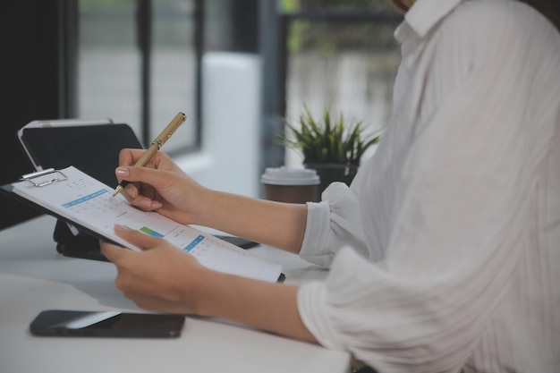 Portrait d'une jeune femme asiatique travaillant à la main sur une tablette informatique dans un bureau moderne. Faire un rapport d'analyse comptable sur les données d'investissement immobilier Concept de systèmes financiers et fiscaux