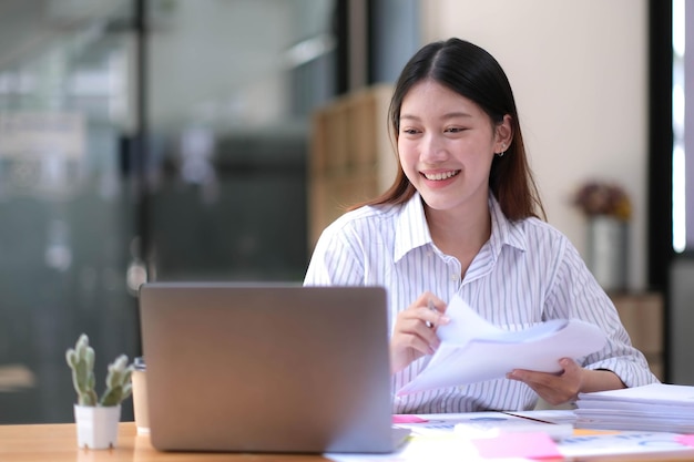 Portrait d'une jeune femme asiatique travaillant sur un ordinateur portable au bureau