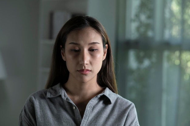 Portrait d'une jeune femme asiatique triste et inquiète dans le salon