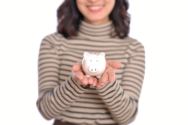 Portrait de jeune femme asiatique uniforme décontracté tenant une tirelire blanche isolée sur fond blanc Concept d'économie d'argent financier et bancaire