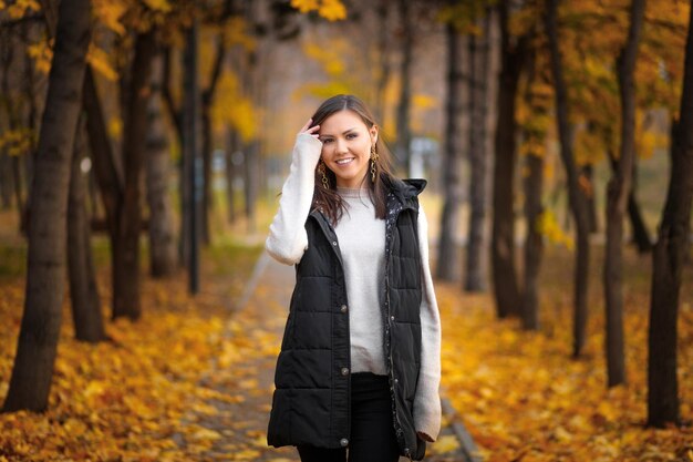 Portrait d'une jeune femme d'Asie centrale dans un parc d'automne sur une allée avec des feuilles d'automne tombées