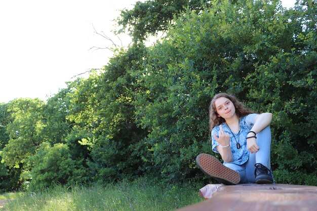 Photo portrait d'une jeune femme assise et jetant un doigt du milieu