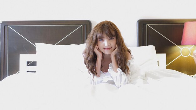 Photo portrait d'une jeune femme assise sur le lit à la maison