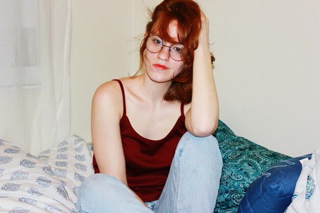 Photo portrait d'une jeune femme assise sur le lit à la maison