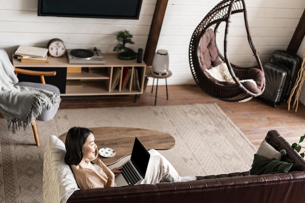 Portrait d'une jeune femme assise à la maison avec une fille asiatique pour ordinateur portable utilisant un ordinateur dans son salon ...