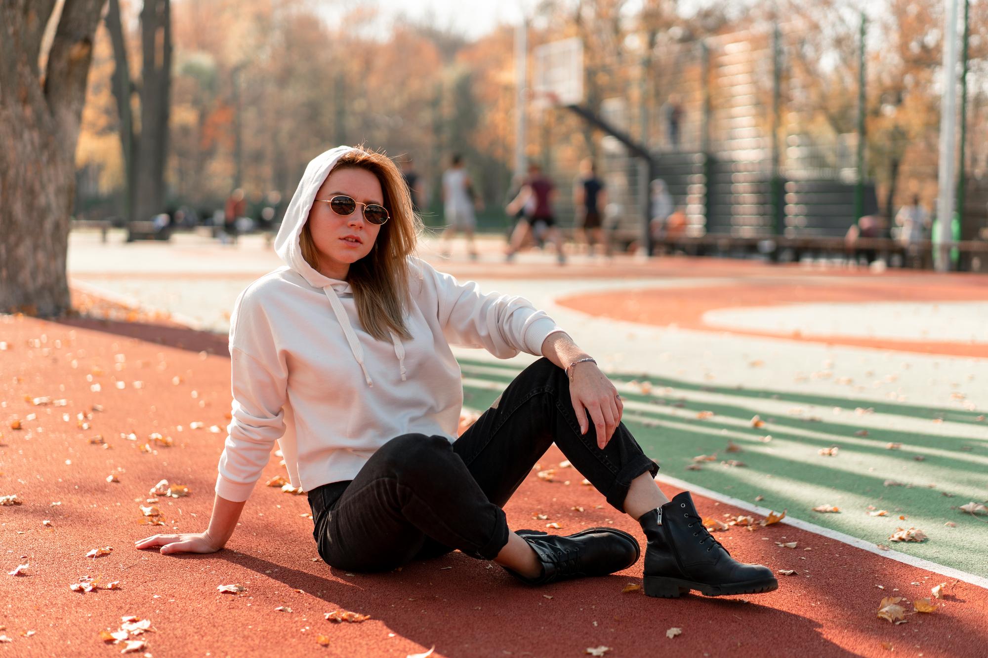 Photo portrait d'une jeune femme assise sur un terrain de jeu en automne