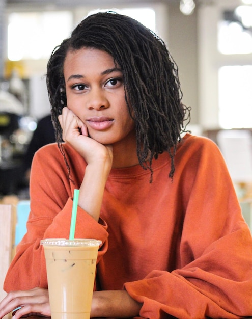 Portrait d'une jeune femme assise avec un verre dans un café