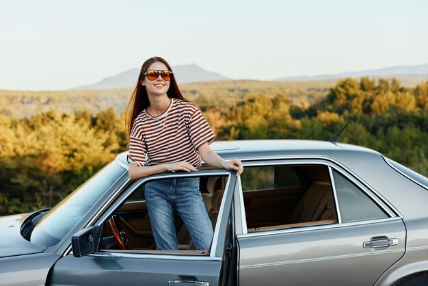 Portrait d'une jeune femme assise sur une voiture