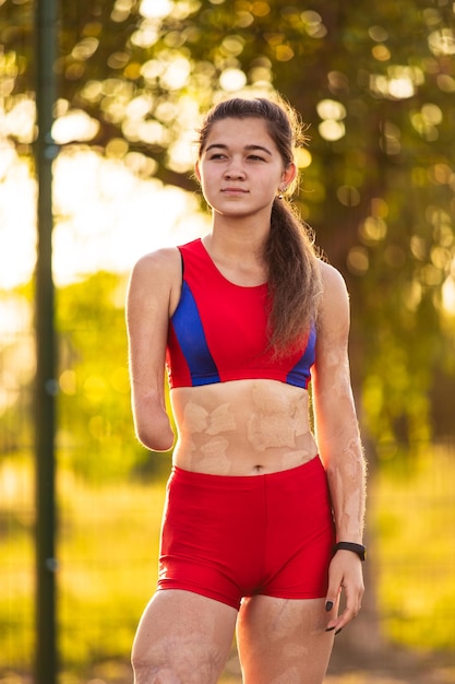 Portrait jeune femme athlète avec un bras amputé et des brûlures sur son corps Entraînement en plein air au coucher du soleil