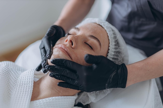 portrait d'une jeune femme attrayante recevant un massage facial avec de la crème