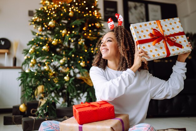 Portrait de jeune femme au chapeau de père Noël avec cadeau à l'arbre de Noël Noël Nouvel an