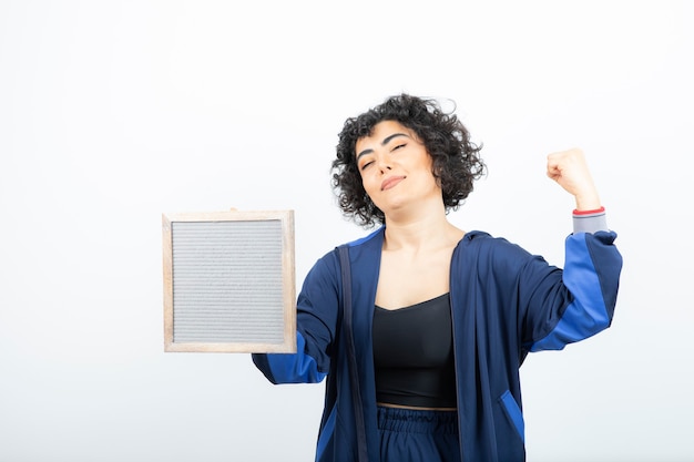 Portrait d'une jeune femme aux cheveux bouclés avec cadre debout.