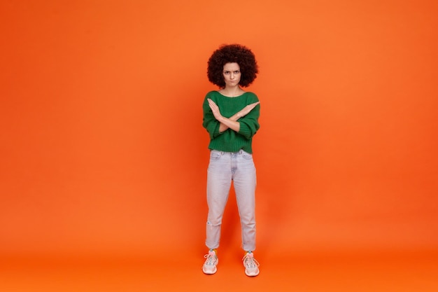 Portrait de jeune femme aux cheveux bouclés émotionnelle sur fond orange