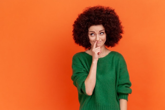 Portrait de jeune femme aux cheveux bouclés émotionnelle sur fond orange