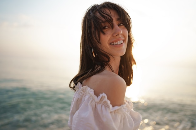 Portrait de jeune femme aux cheveux brune à la plage au coucher du soleil