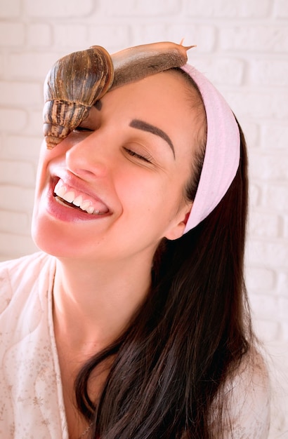 portrait de jeune femme aux cheveux noirs avec des escargots achatina géant sur son visage