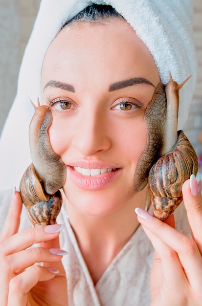 portrait de jeune femme aux cheveux noirs avec des escargots achatina géant sur son visage