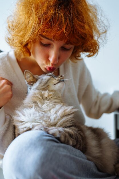 Portrait d'une jeune femme aux cheveux roux et attrayante avec un chat domestique moelleux