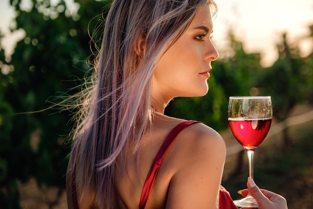 Portrait De Jeune Femme De Beauté En Robe Rouge Dans Les Vignes En Saison Estivale. Profiter D'une Visite De Dégustation Dans Une Magnifique Région Viticole.