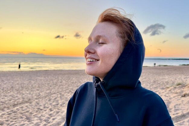 Portrait d'une jeune femme belle, une adolescente qui se détend sur une plage naturelle, un sourire en arrière-plan.