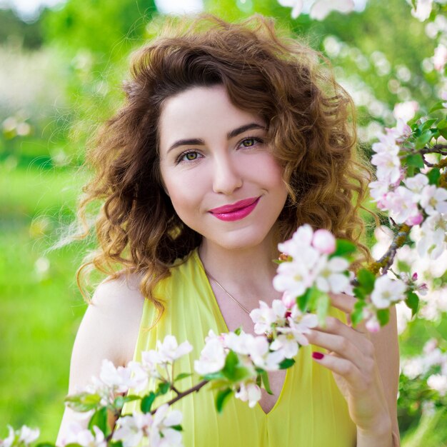 Portrait de jeune femme belle avec arbre en fleurs dans le jardin