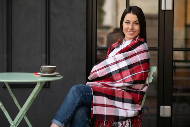 Portrait de jeune femme belle assise dans un café en plein air de boire du café