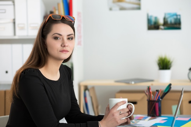 Portrait de jeune femme belle, boire du thé tout en travaillant