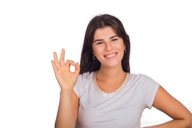 Portrait de jeune femme belle faisant le geste OK en studio.