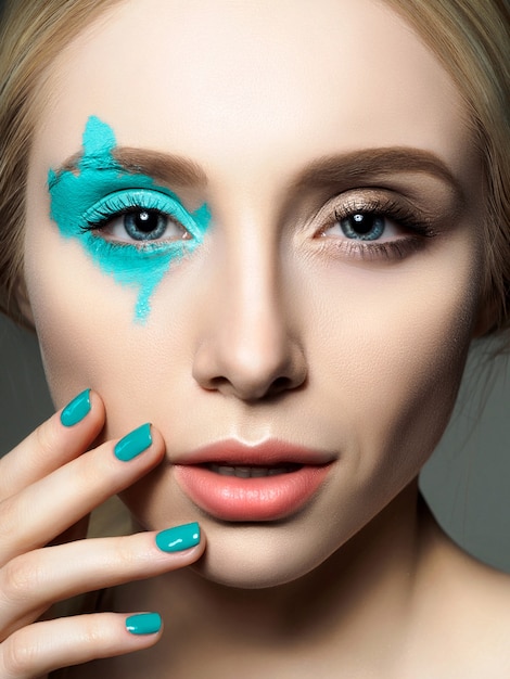 Portrait de jeune femme belle avec mode composent toucher son visage. Modèle posant sur fond gris.