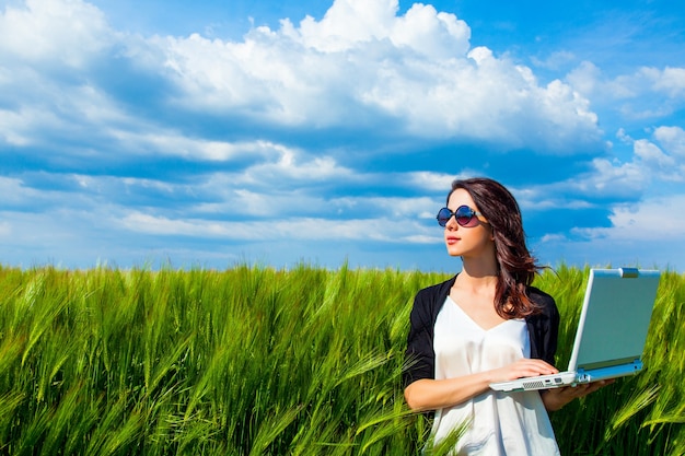 Portrait de jeune femme belle avec ordinateur portable sur le terrain