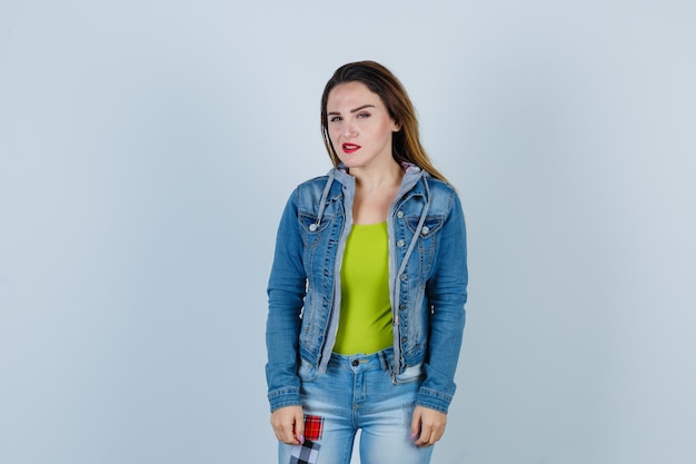 Portrait de jeune femme belle regardant à l'avant en tenue de denim et à la vue de face ennuyée